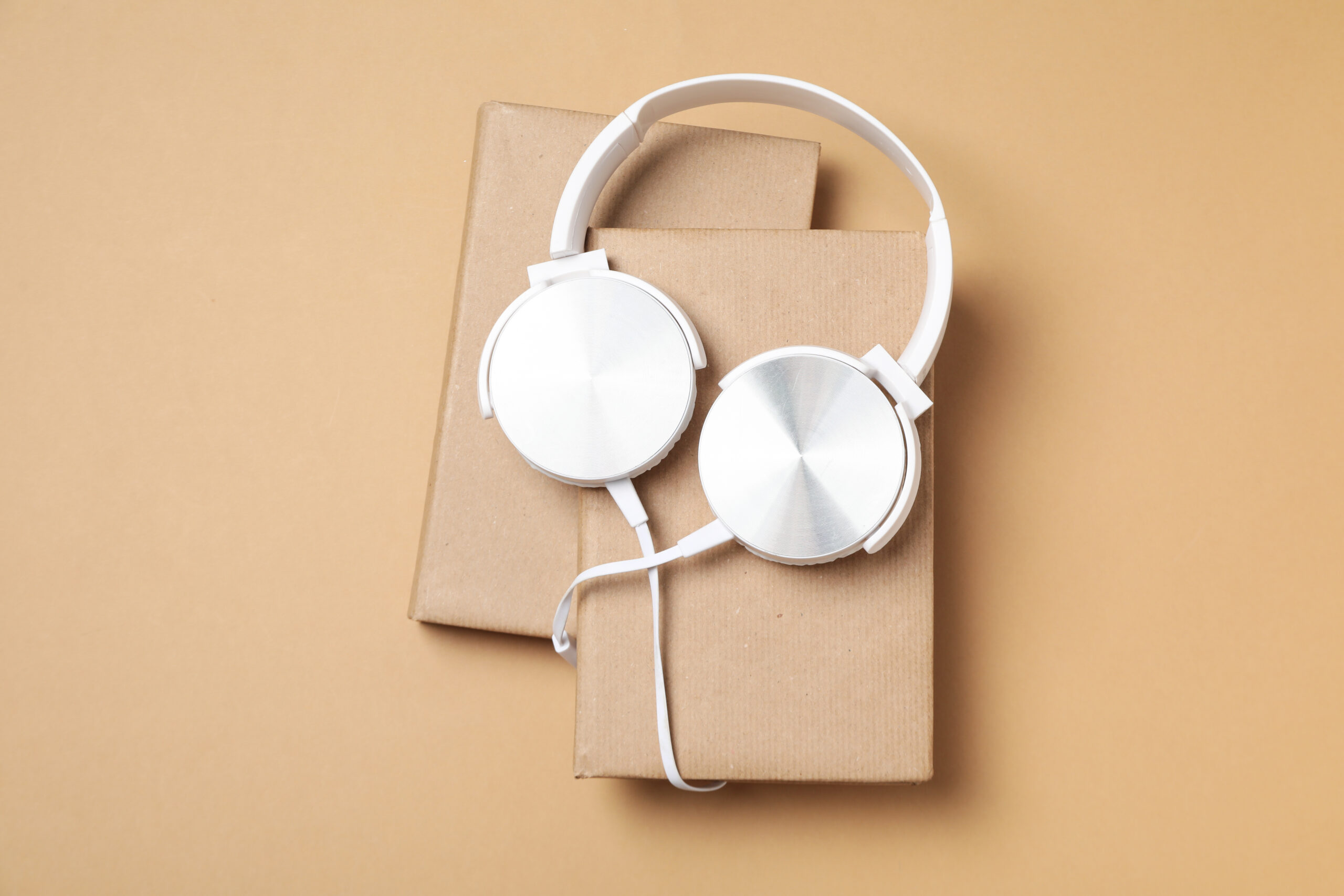 headphones on books on beige background top view 2026 03 24 21 37 09 utc