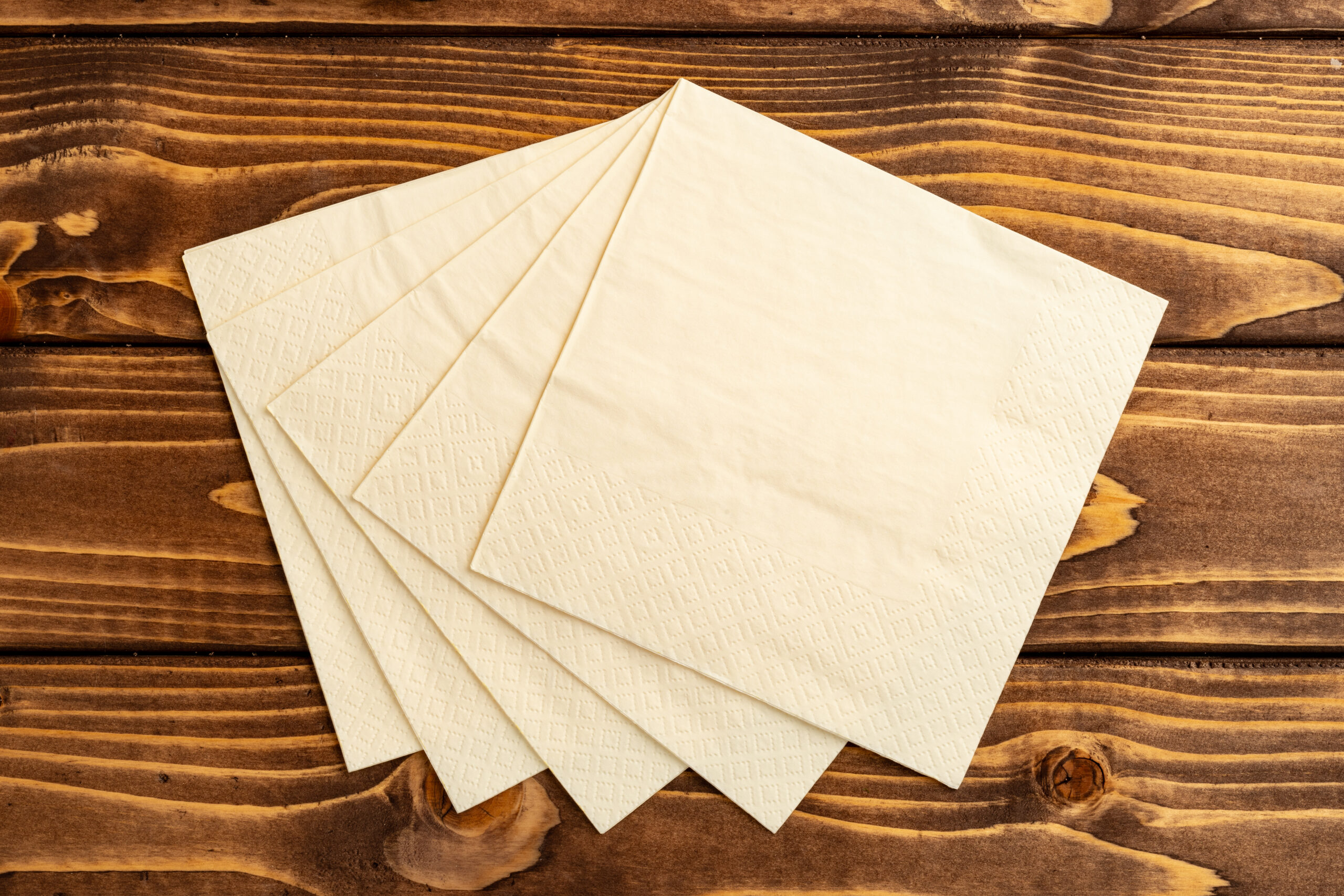stack of paper square napkins on brown wooden back 2026 01 08 05 31 25 utc