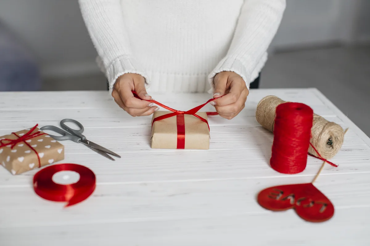 hands-packing-gift-with-red-ribbon-table.jpg