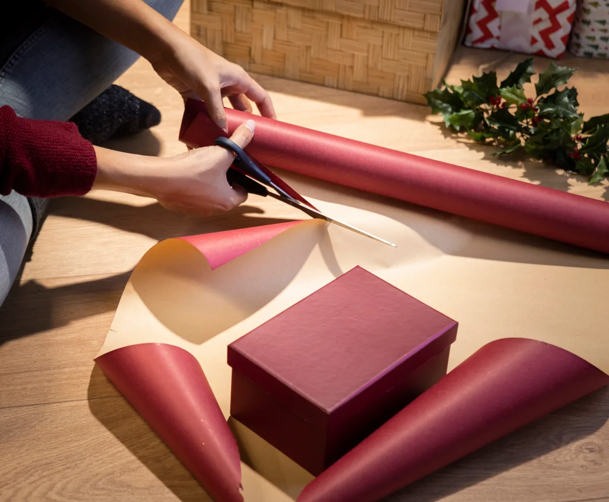 high-angle-woman-cutting-paper-wrap-gifts.webp