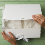 box with wedding dress and female hands on green b 2026 01 09 07 46 11 utc