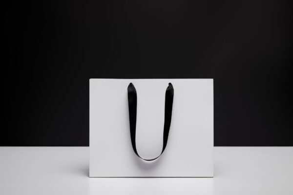 one white shopping bag on white table isolated on 2026 01 06 00 44 04 utc