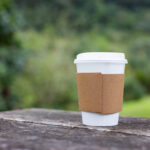 a paper cup of coffee with green park background 2026 01 09 07 34 55 utc