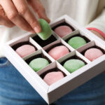 woman holding delicious mochi above box closeup 2026 01 15 10 05 00 utc