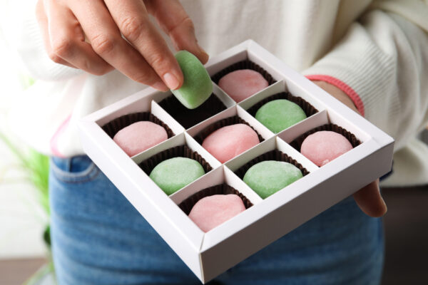 woman holding delicious mochi above box closeup 2026 01 15 10 05 00 utc