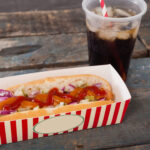 close up of hot dog and cold drink on wooden table 2026 03 26 11 48 15 utc