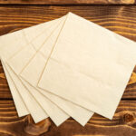 stack of paper square napkins on brown wooden back 2026 01 08 05 31 25 utc