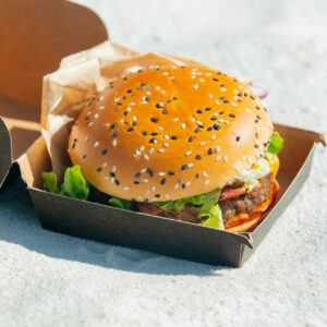 tasty burger in box on white sand on beach 2026 01 05 04 32 17 utc