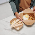 woman opening box of food 2026 03 18 05 30 43 utc