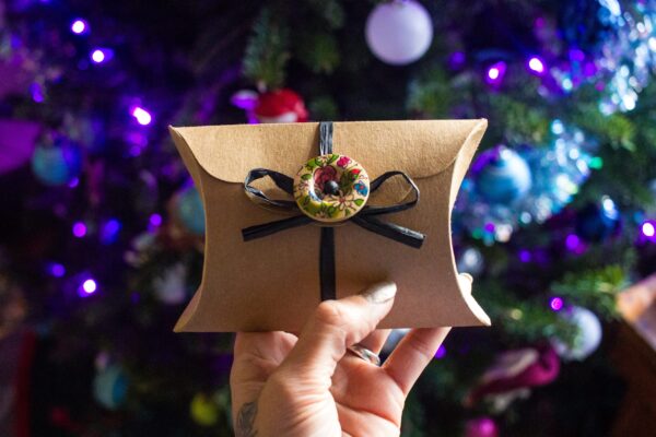 festive gift being held in front of tree 2026 03 16 00 38 06 utc