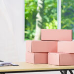 stacked pink boxes on a desk by a window 2026 03 18 17 43 56 utc