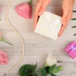 woman s hands holding a gift box on gray wooden ba 2026 03 26 07 18 57 utc
