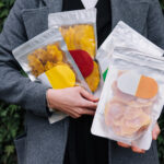 dried fruit snack packages held in front of foliag 2026 01 08 02 40 14 utc