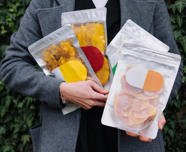 dried fruit snack packages held in front of foliag 2026 01 08 02 40 14 utc