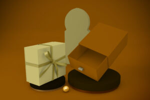 Sage green rigid gift box with satin ribbon and an open amber drawer box with pull tab on dark display podiums.